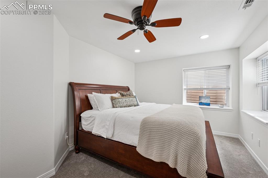 Image 41 of 50: Carpeted bedroom featuring multiple windows, ceiling fan, and recessed ligh
