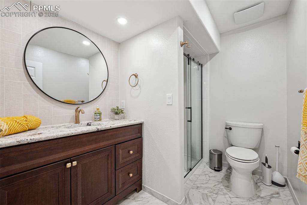 Image 42 of 50: Bathroom featuring marble look tile flooring, vanity, a stall shower, and r