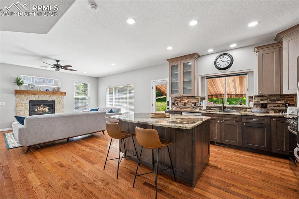 Image 7 of 50: Kitchen featuring a breakfast bar, decorative backsplash, light wood-style