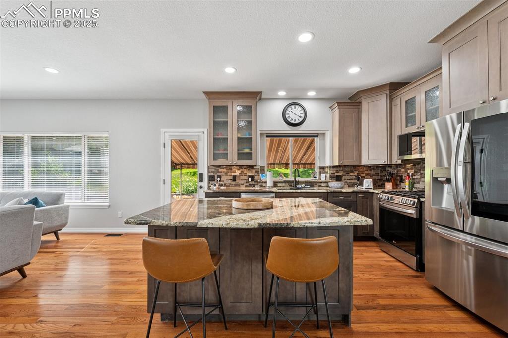 Image 9 of 50: Kitchen featuring appliances with stainless steel finishes, a kitchen bar,