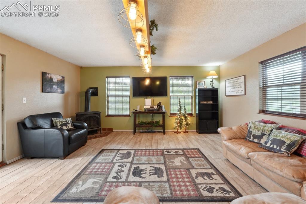 Image 12 of 38: Living area with a wood stove, hardwood / wood-style flooring, a textured c