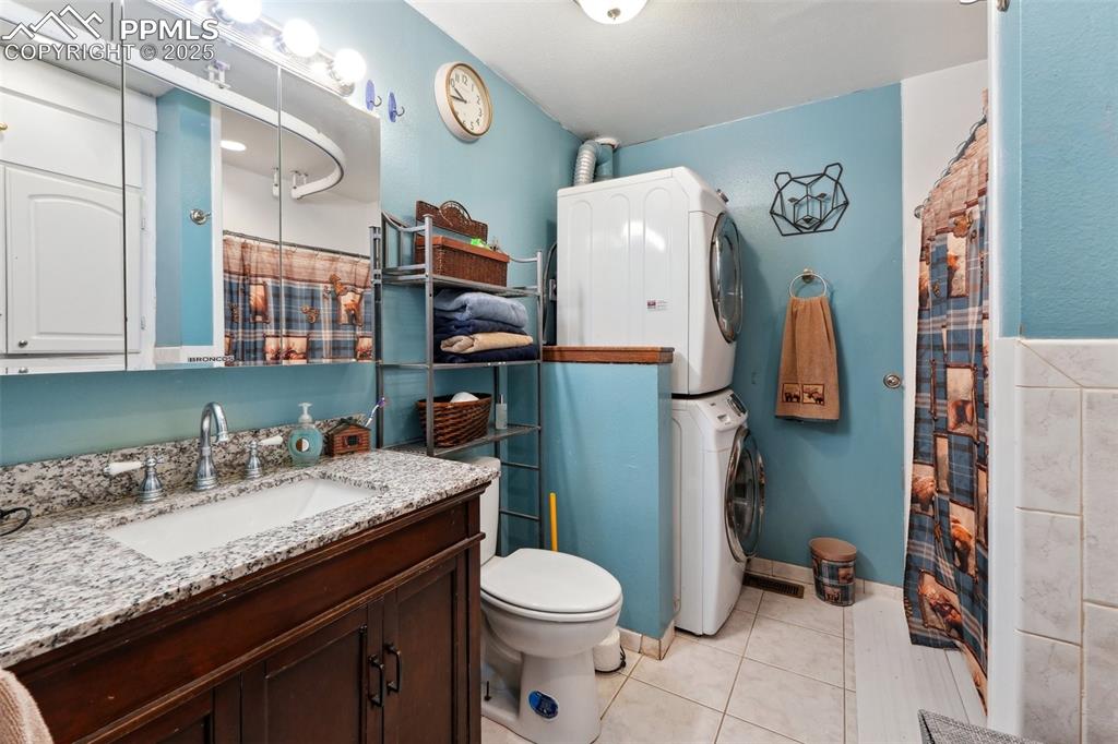 Image 17 of 38: Full bathroom with stacked washing machine and dryer, vanity, tile patterne