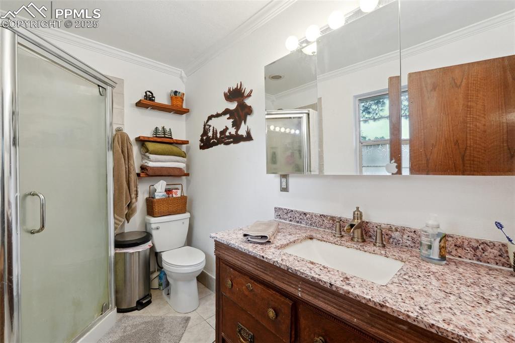 Image 20 of 38: Full bath featuring vanity, crown molding, toilet, a stall shower, and tile