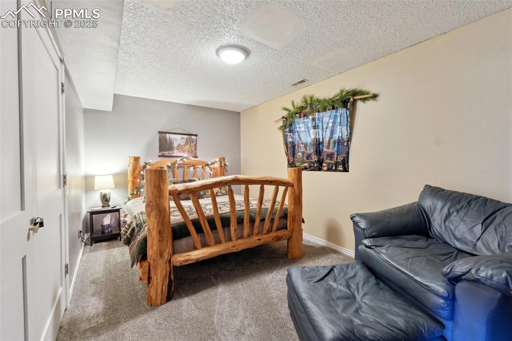Image 21 of 38: Carpeted bedroom with a textured ceiling and baseboards