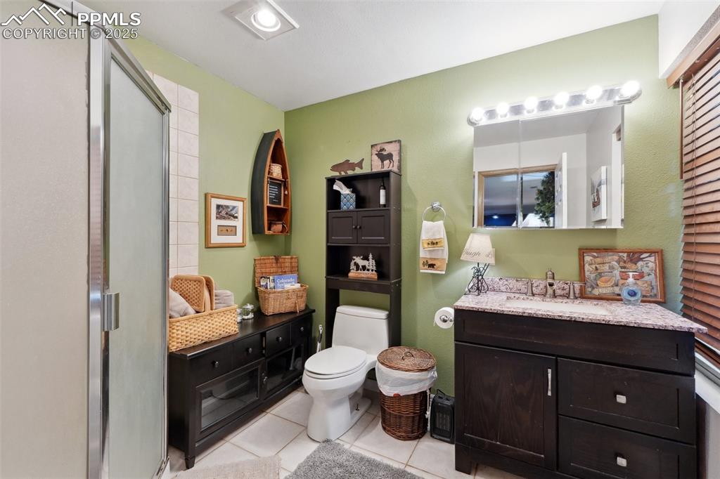 Image 27 of 38: Full bathroom with tile patterned flooring, vanity, toilet, and a shower st