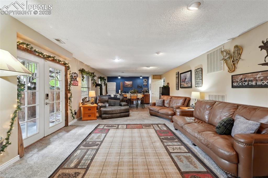 Image 28 of 38: Living room featuring carpet floors, a textured ceiling, french doors, and 