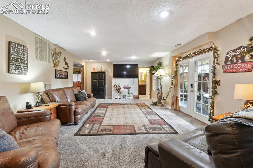 Image 29 of 38: Carpeted living area featuring french doors, a textured ceiling, and recess