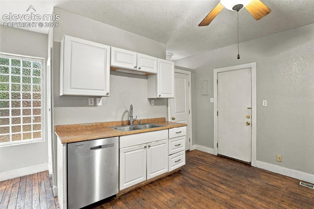Image 10 of 34: Galley kitchen with white cabinetry, stainless steel dishwasher, double bas