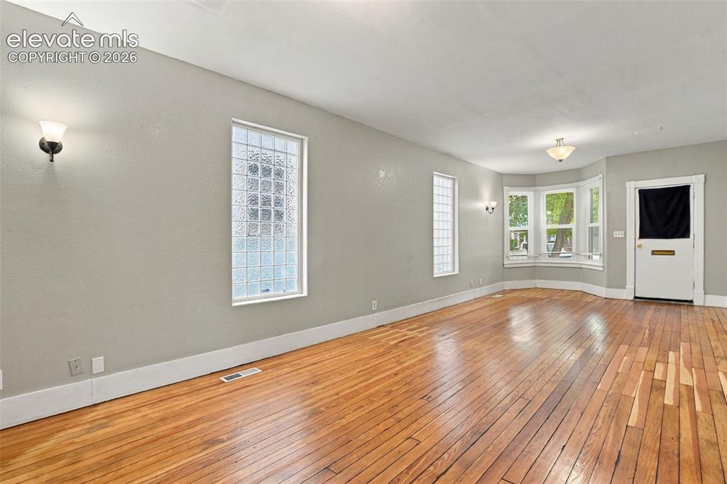 Image 12 of 34: Hardwood flooring throughout, multiple wall sconces, ceiling-mounted light