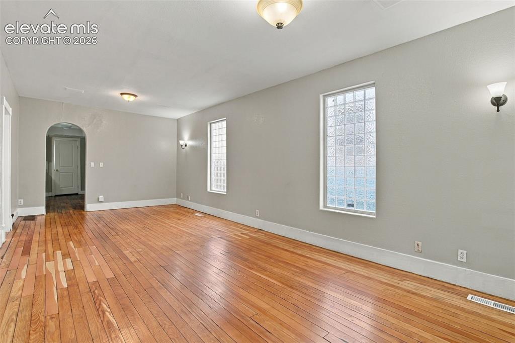 Image 18 of 34: Hardwood flooring throughout, arched doorway, two decorative wall sconces, 