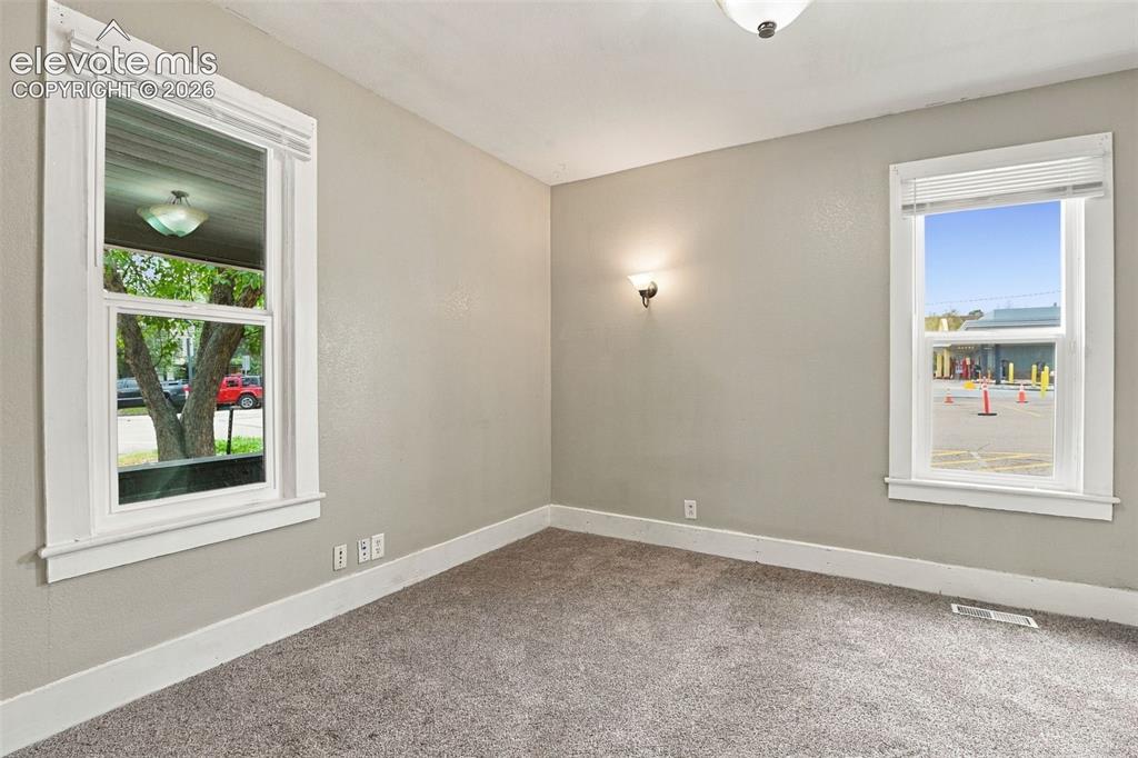 Image 21 of 34: Plush carpet flooring, light neutral wall paint, two windows with white tri