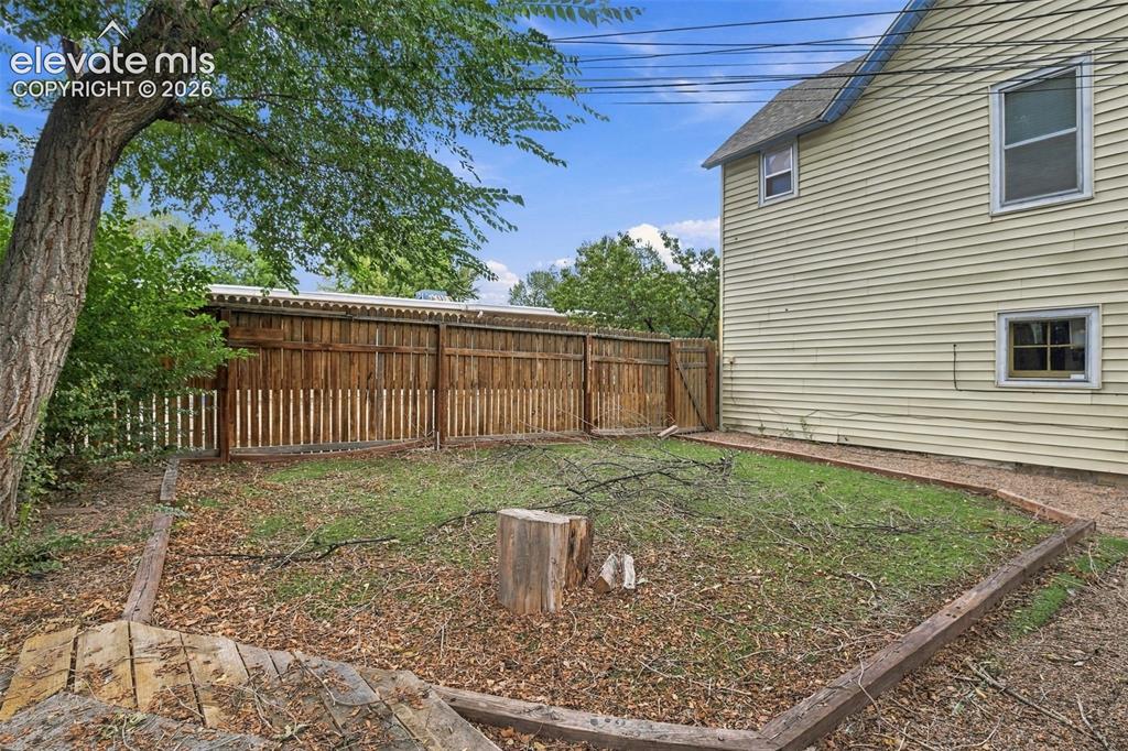 Image 29 of 34: Fenced yard with wood fencing and a mature tree