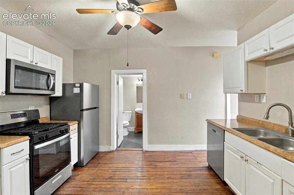 Image 3 of 34: Kitchen featuring wood-finish flooring, white cabinetry, a ceiling fan, and