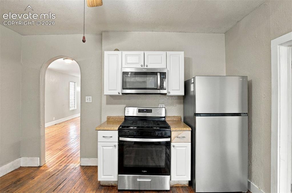 Image 6 of 34: Kitchen featuring a stainless steel refrigerator, white cabinetry, and an e