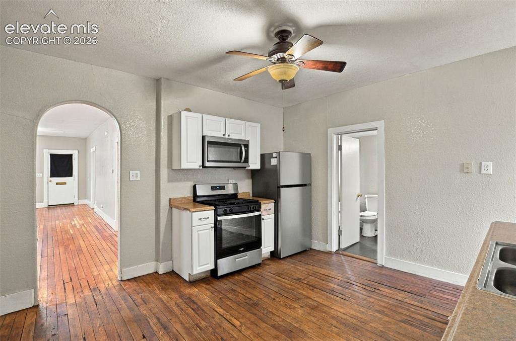 Image 7 of 34: Wood-finish flooring, white cabinetry, stainless steel appliances, and a ce
