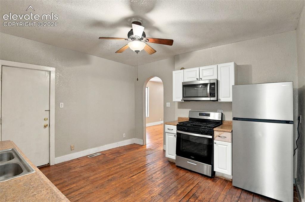 Image 8 of 34: Kitchen featuring wood-finish flooring, white cabinetry, stainless steel ra