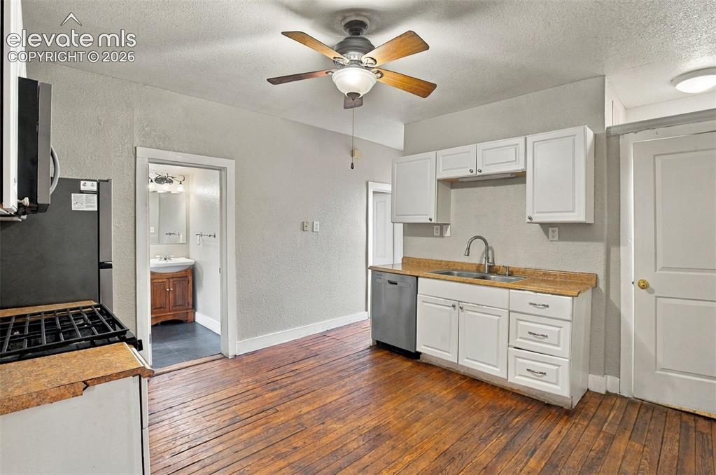 Image 9 of 34: Kitchen featuring wood-finish flooring, white cabinetry, a double basin sin