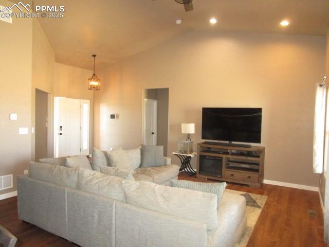 Image 2 of 6: Living area with wood finished floors and high vaulted ceiling
