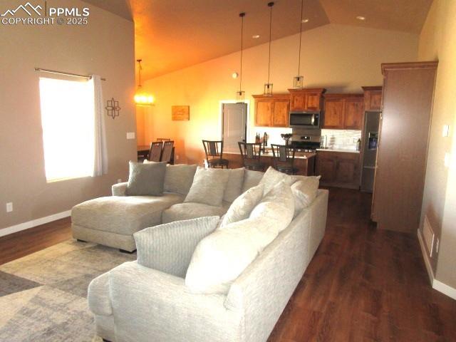 Image 5 of 6: Living area with dark wood-style floors and high vaulted ceiling