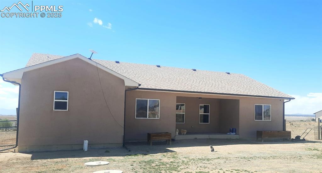 Image 6 of 6: Rear view of property featuring a shingled roof and stucco siding