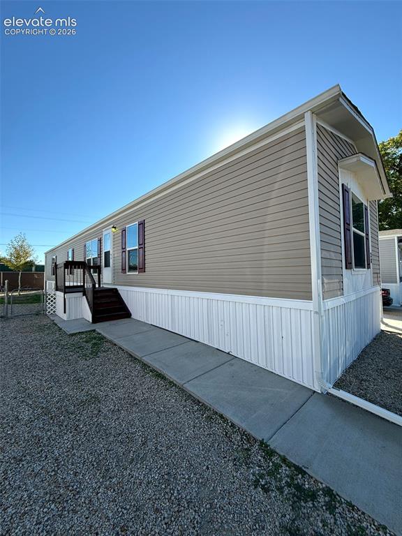 Caption: Exterior features include horizontal vinyl siding, contrasting shutters, a concrete walkway, and an 