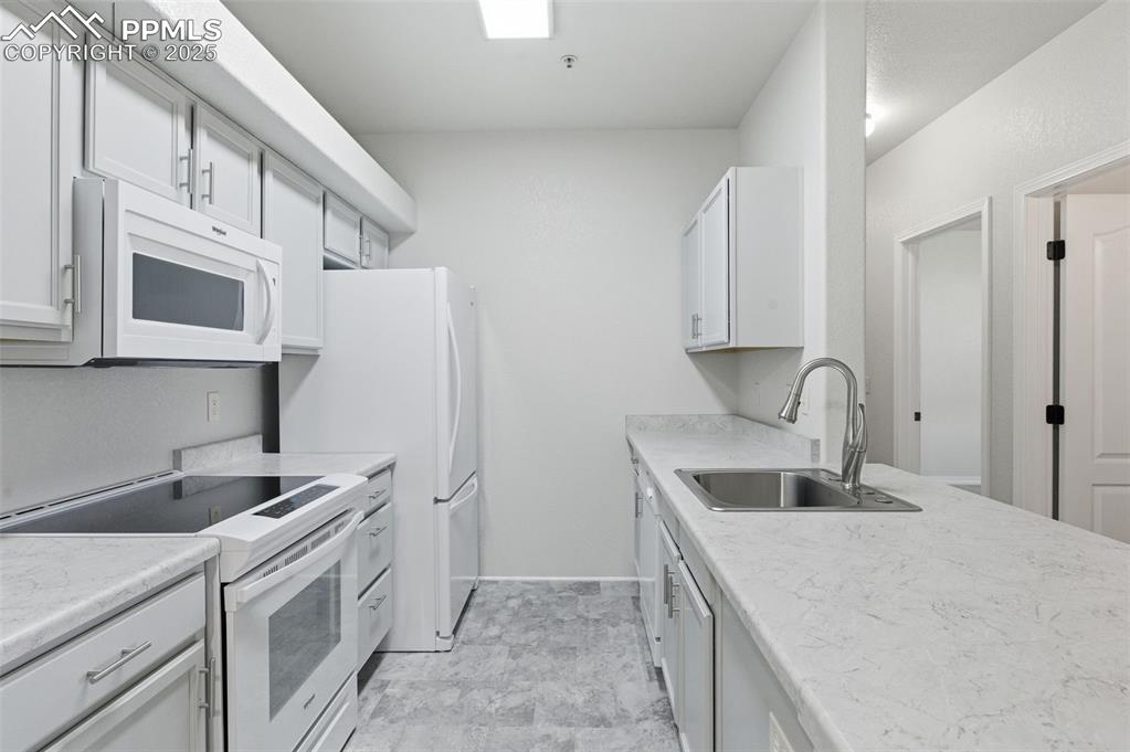 Image 11 of 39: Kitchen featuring white appliances, light countertops, and white cabinetry