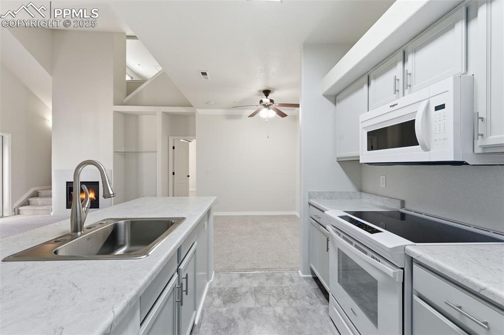 Image 12 of 39: Kitchen featuring white appliances, light countertops, ceiling fan, white c
