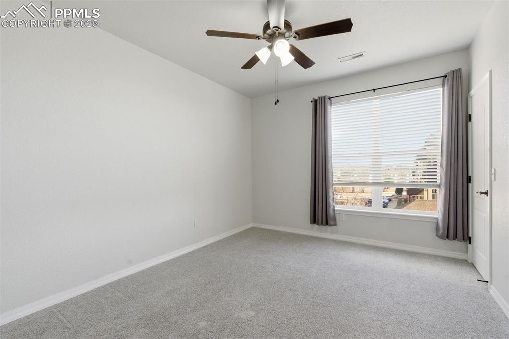 Image 21 of 39: Empty room with light colored carpet and ceiling fan