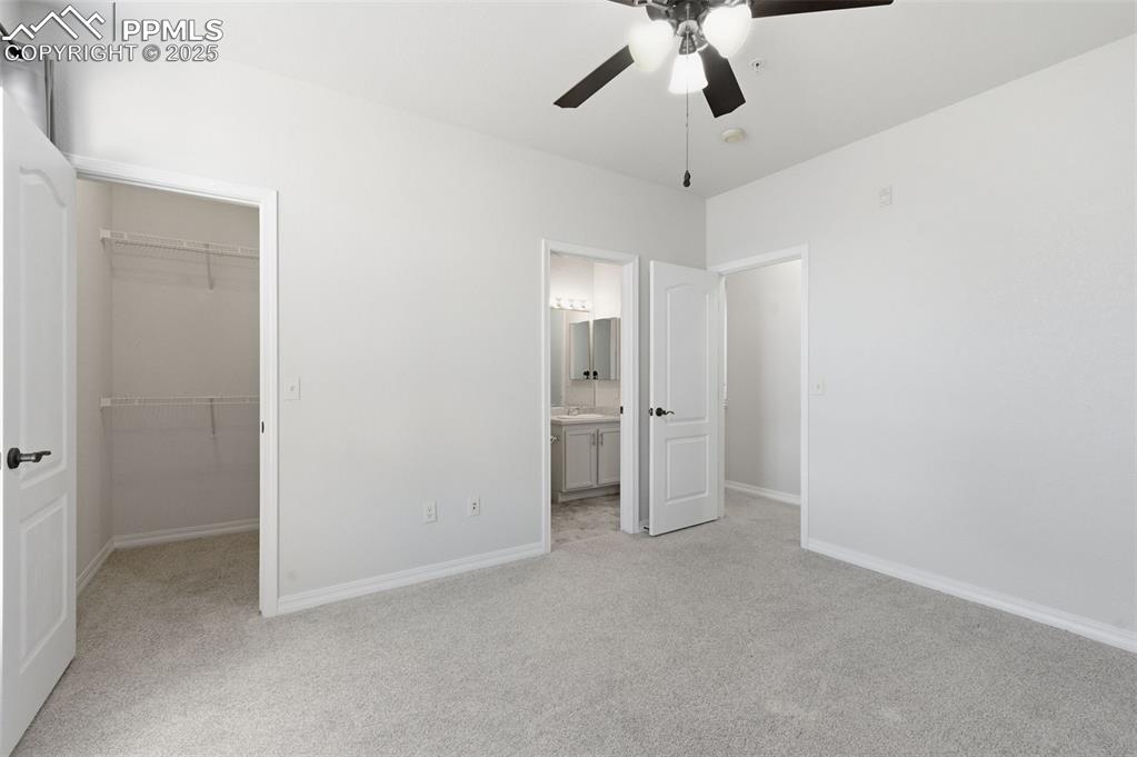Image 22 of 39: Unfurnished bedroom with light carpet, a spacious closet, a ceiling fan, an