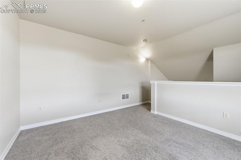 Image 31 of 39: Unfurnished room with carpet flooring and vaulted ceiling