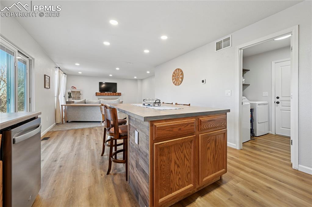 Image 13 of 37: Kitchen with brown cabinets, stainless steel dishwasher, a center island, a