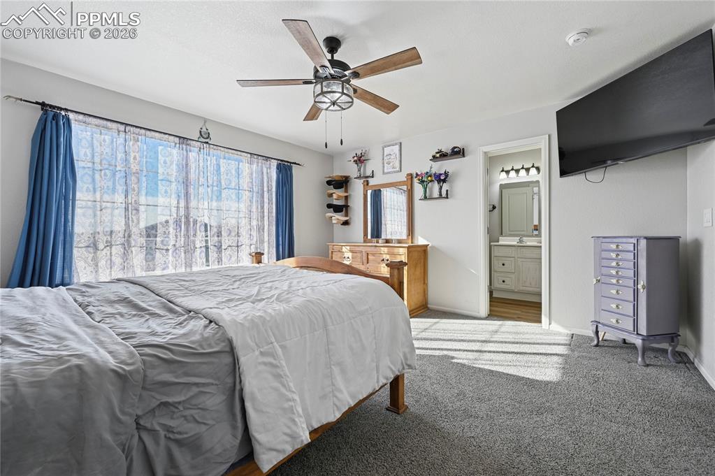 Image 18 of 37: Bedroom featuring a ceiling fan, carpet flooring, and connected bathroom