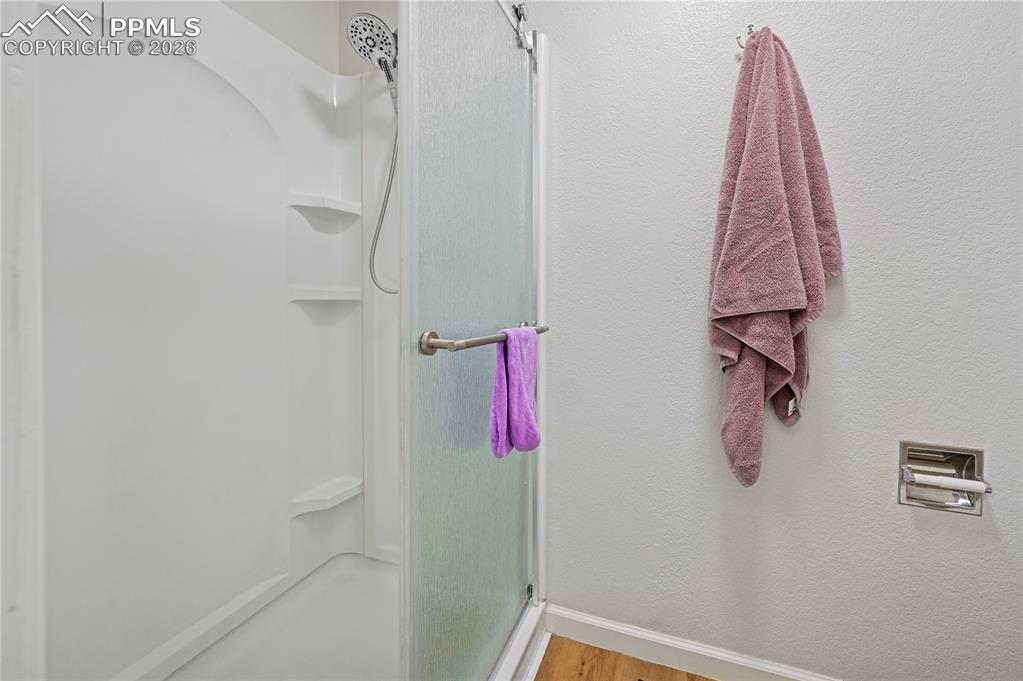 Image 20 of 37: Full bathroom with a shower stall, light wood-style floors, and a textured