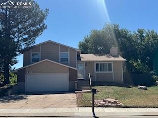 Caption: Split level home with concrete driveway, a garage, and a front lawn