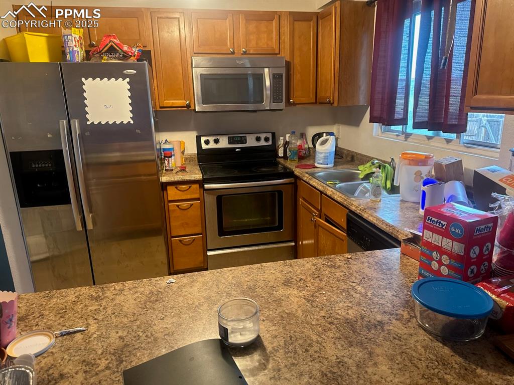 Image 2 of 6: Kitchen with stainless steel appliances, dark stone counters, and brown cab
