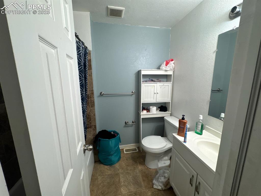 Image 5 of 6: Full bathroom featuring vanity, a shower with shower curtain, a textured ce