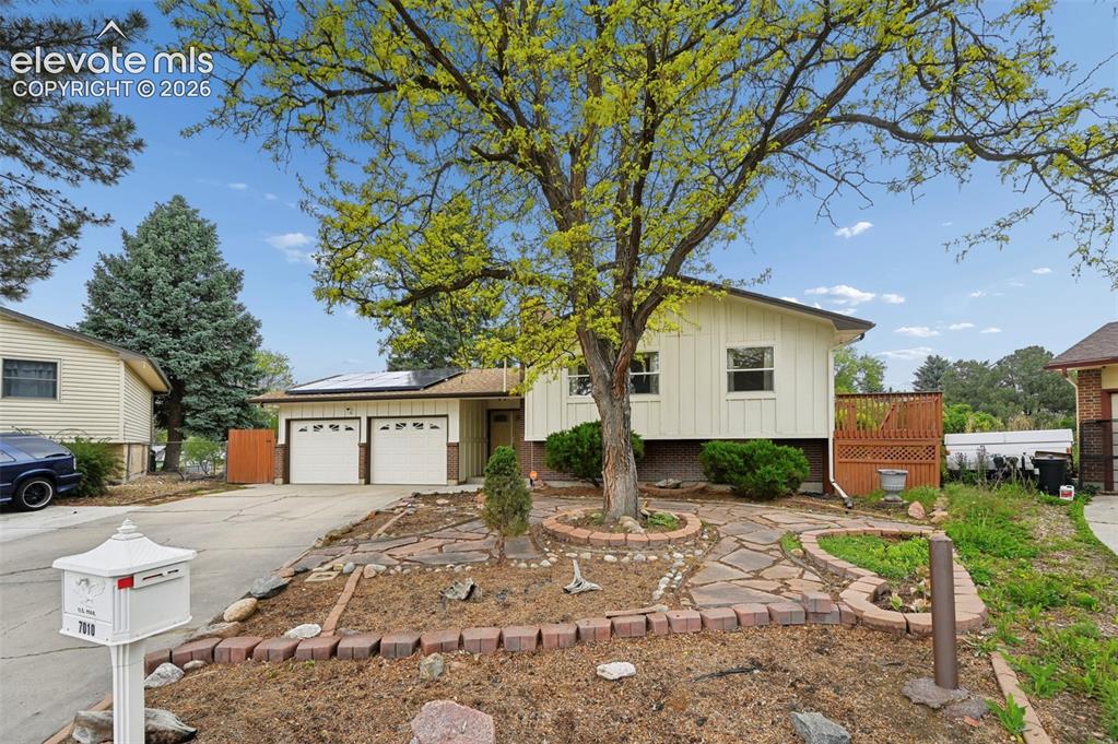 Image 1 of 50: Split-level residence featuring a two-car garage with panel doors and a mat