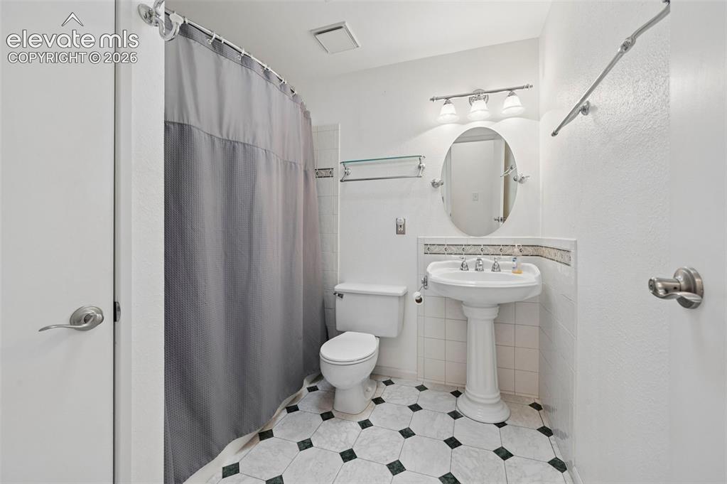 Image 13 of 50: Bathroom featuring a pedestal sink, oval mirror, and a three-light vanity f