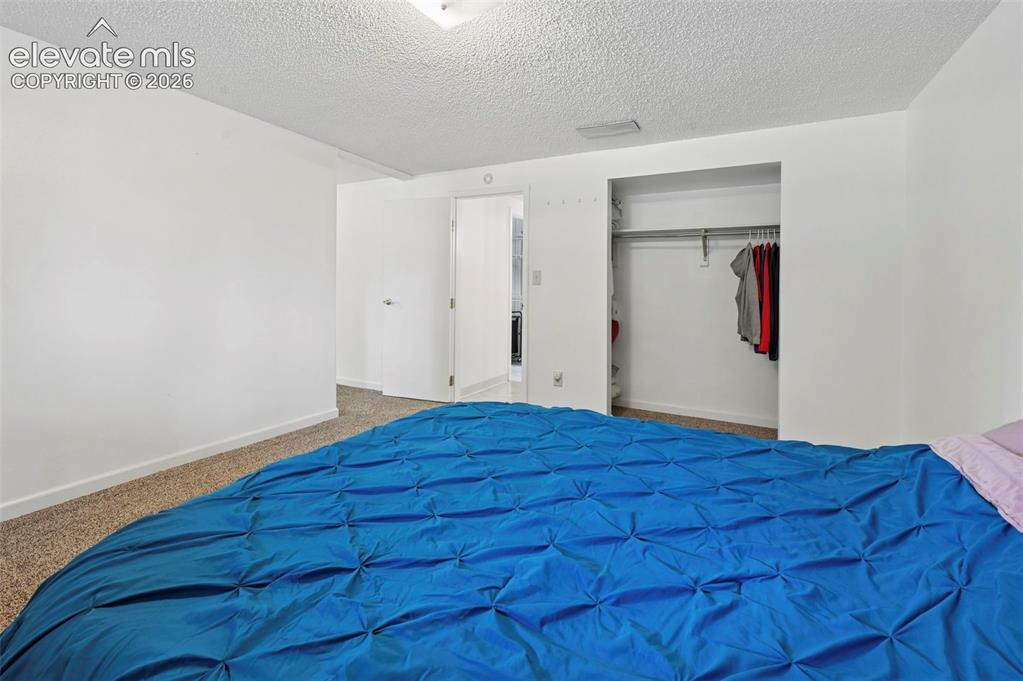 Image 25 of 50: Carpeted bedroom with a built-in closet featuring a clothes rod and shelvin