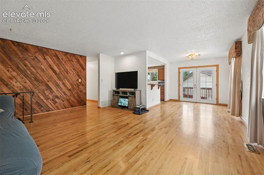 Image 31 of 50: Spacious room featuring wood-finish flooring and an accent wall with diagon