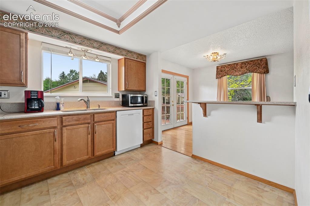 Image 36 of 50: Kitchen featuring light wood cabinetry, a built-in dishwasher, and a double