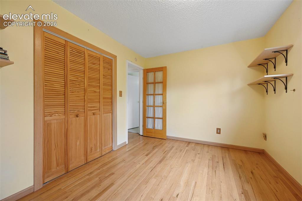 Image 38 of 50: Hardwood flooring throughout, featuring louvered bi-fold closet doors, a pa