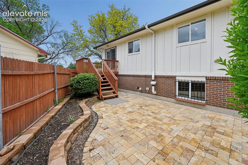 Image 4 of 50: Multi-level outdoor patio featuring herringbone-patterned pavers, a wood de