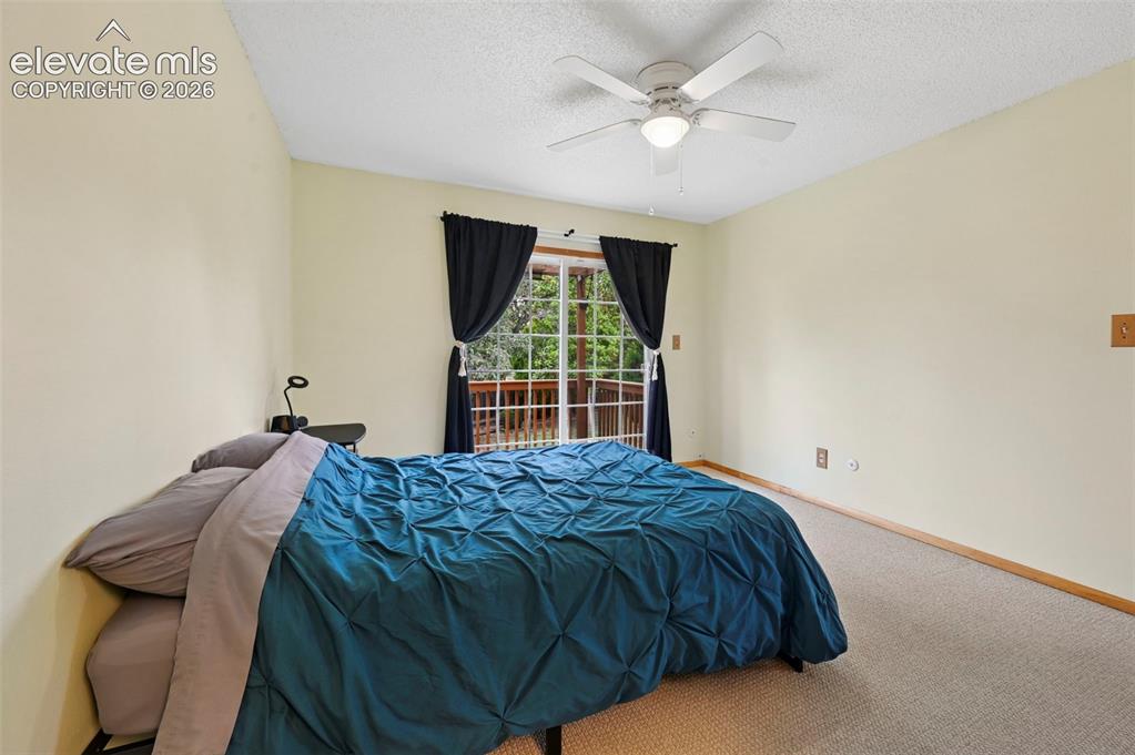 Image 42 of 50: Carpeted bedroom with a sliding glass door leading to an outdoor deck