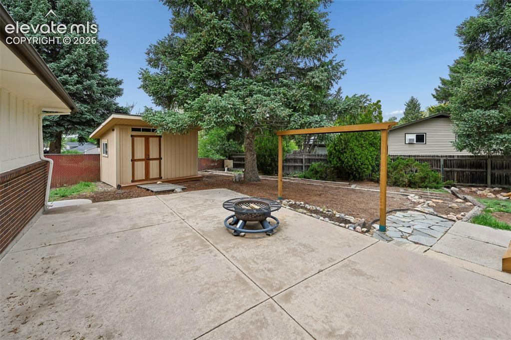 Image 45 of 50: Expansive concrete patio area with a freestanding storage shed featuring do