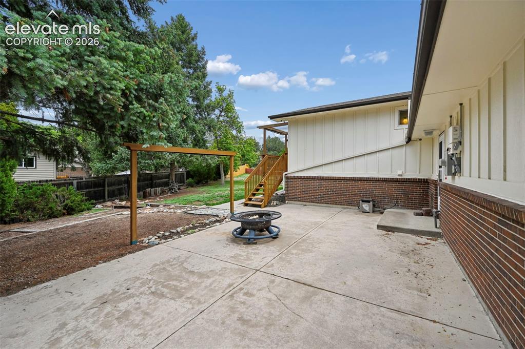 Image 46 of 50: Expansive concrete patio with a built-in fire pit, offering direct access t