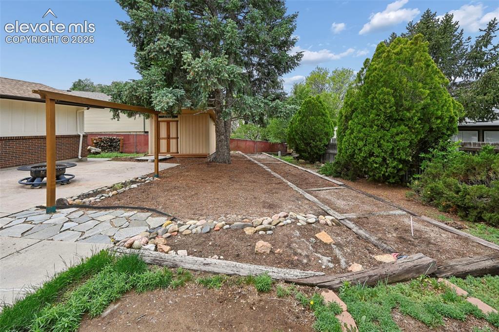 Image 48 of 50: Expansive backyard featuring a concrete patio, stone pathway, and a wooden