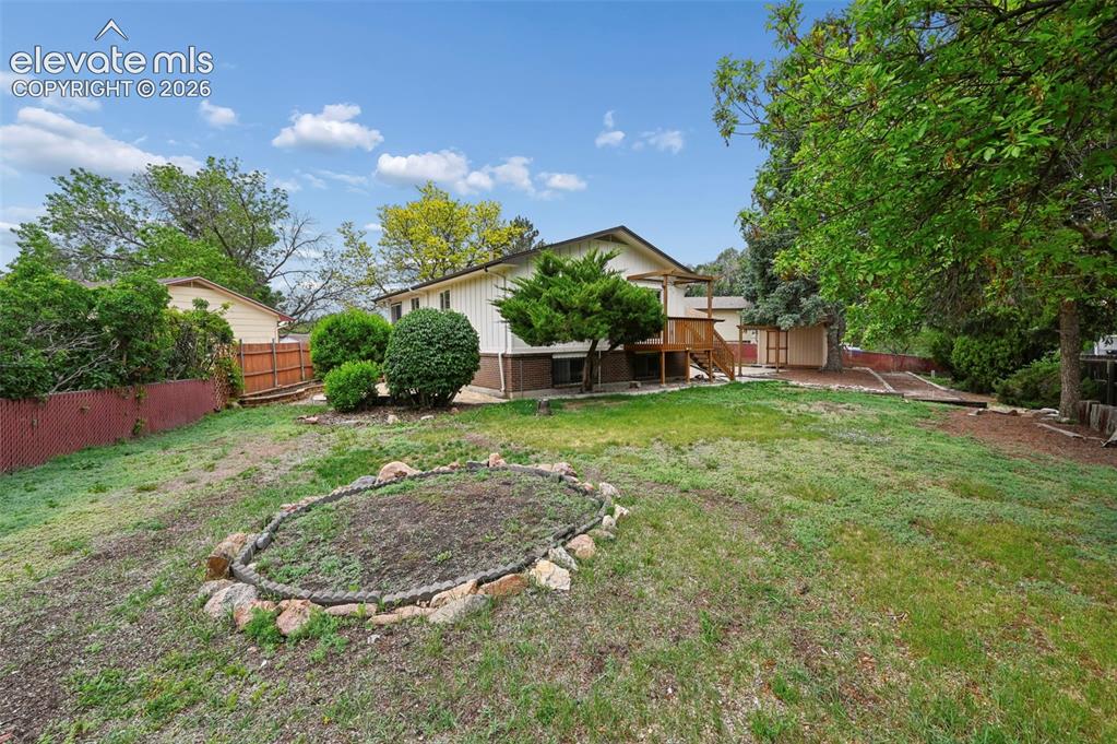 Image 50 of 50: Expansive backyard featuring a rock-lined garden bed, mature trees, and a m