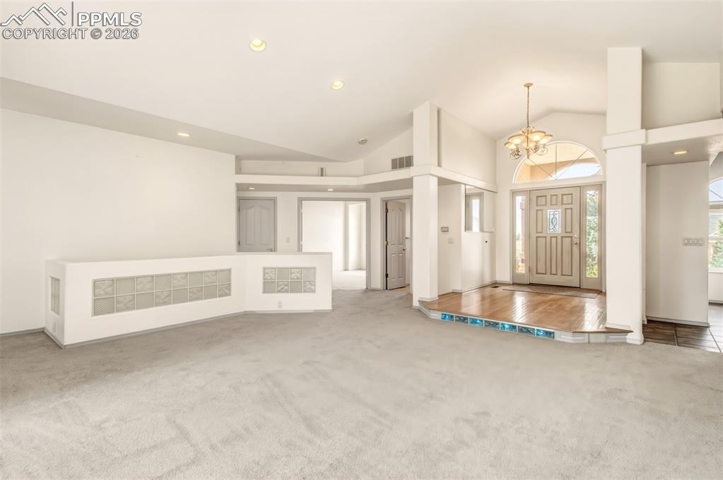 Image 11 of 35: Entrance foyer with hanging lights, light colored carpet, and vaulted ceili