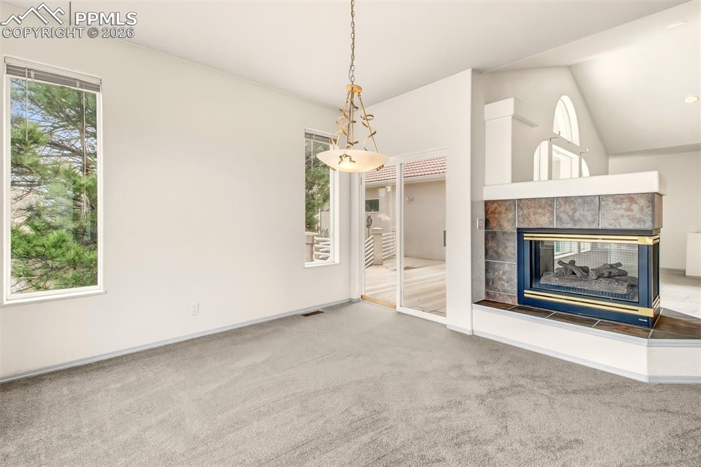 Image 14 of 35: Unfurnished living room with a tile fireplace, carpet, lofted ceiling, and 